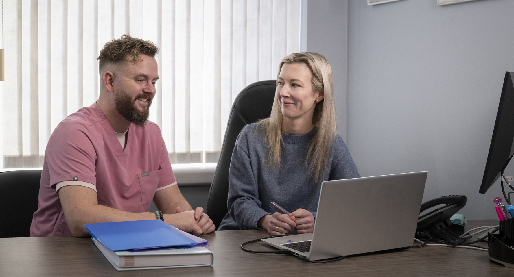 Dr. Heather Poushay and a colleague sitting at a desk in an office